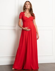 a pregnant woman in a red dress standing against a wall