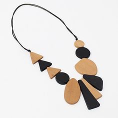 "Tan Long Alexis Necklace A fun necklace for the art lover. Geometric wood beads are hand painted in black and tan and stacked together in a unique pattern on an adjustable black wax cord. Wear it long or short, you can't go wrong. Finish your look with coordinating statement earrings or a fun bracelet! Adjustable Length: 24\"-38\" DW22N03 TAN Care Instructions: Remove Sylca Statement jewelry when applying perfumes, creams, washing hands etc. Do not store in direct sunlight. To restore color and Adjustable Black Wooden Jewelry, Artsy Handmade Black Necklace, Black Necklaces With Wooden Beads, Unique Black Necklaces With Wooden Beads, Acrylic Necklace, Wood And Acrylic, Washing Hands, Acrylic Necklaces, Fun Bracelet