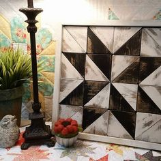 a table topped with a vase filled with fruit next to a wall mounted art piece