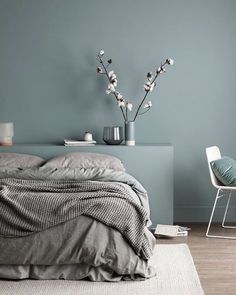 a bed sitting next to a blue wall in a bedroom