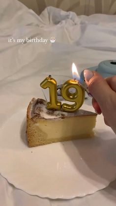 a person lighting a candle on top of a piece of cake with the number 19