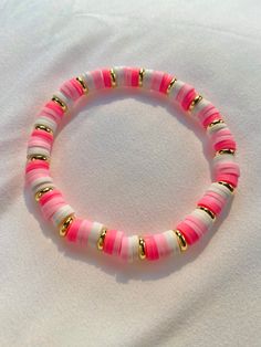 a pink and white beaded bracelet with gold accents on a white background, close up