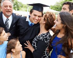 a group of people standing next to each other in front of a man wearing a graduation cap