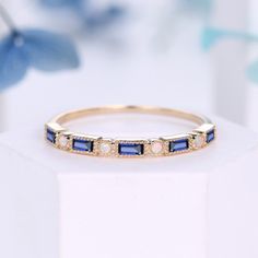 a gold ring with blue and white stones on it, sitting on top of a table