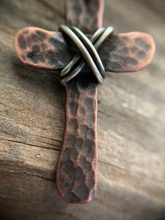 "Show your faith with this humble, rustic cross. I hammer and forge each of these crosses by hand from pure, organic copper and wrap it with 925 Sterling silver. Each cross is finished with a rustic patina which gives it an antiqued look. These are perfect for men or women. Dark brown cowhide leather cording is 24\" in length and is adjustable. Necklace slips over the head. If you would like another style chain like a ball chain or cable chain please message me before ordering. Prices may vary b Artisan Brown Cross Jewelry, Rustic Cross Jewelry For Gifts, Rustic Cross Jewelry Gift, Handmade Artisan Cross Pendant Necklace, Rustic Cross, Brown Cowhide, Christian Jewelry, Adjustable Necklace, Cable Chain