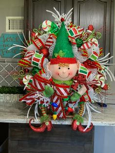 a christmas wreath with an elf on top and candy canes in the bottom, sitting on a table