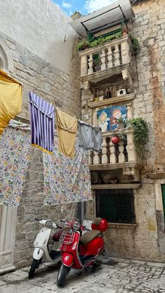 a scooter parked in front of a building with clothes hanging from it's balconies