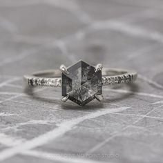 an engagement ring with a square cut diamond surrounded by small white diamonds on a gray background