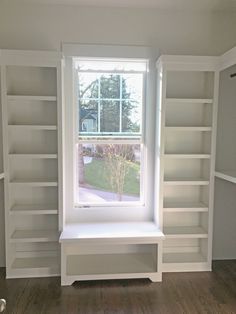 a room with white bookcases and a window