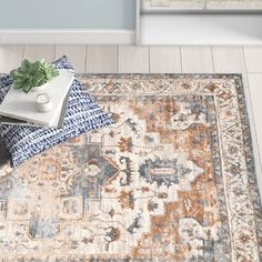 an area rug with a blue, orange and white design on the floor next to a plant