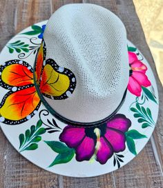 a white hat sitting on top of a wooden table next to a flower covered plate