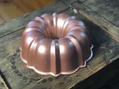 a pink bundt cake sitting on top of a wooden table next to a piece of wood