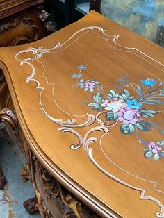 an ornate wooden table with flowers painted on the top and sides, along with other wood furniture