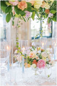 the table is set with flowers, candles and wine glasses for an elegant wedding reception