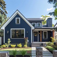 a blue house with steps leading up to the front door and side entryway, surrounded by trees