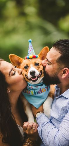 a man and woman kissing with a dog wearing a birthday hat