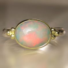 Beautiful, natural, solid Ethiopian opal cabochon set in solid 18k gold bezel on hammered sterling silver band(approx. 26mm wide X 1.5mm thick - hammered from comfy oval wire). Fine silver backsheet underneath stone. Classic solid 18k granule clusters on each side of the opal.  The measures approx. 8 X 10mm. All metal is from recycled sources. This ring is a size 7 and I can stretch to a 7 1/4. Photos have been taken up close for detail. Please refer to dimensions. Attractively boxed. Custom rin Oval Cabochon Opal Ring With Polished Finish, Polished Opal Ring In Oval Cabochon Shape, Yellow Gold Moonstone Ring With Ethiopian Opal, Fine Jewelry Yellow Gold Moonstone Ring With Ethiopian Opal, Opal Oval Cabochon Ring With Polished Finish, Polished Opal Oval Cabochon Ring, Yellow Gold Cabochon Opal Ring, Heirloom Gold Opal Ring With Cabochon, Heirloom Gold Opal Cabochon Ring