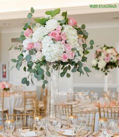 a tall vase filled with pink and white flowers on top of a dining room table