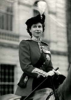 a woman riding on the back of a horse wearing a uniform and feathered hat