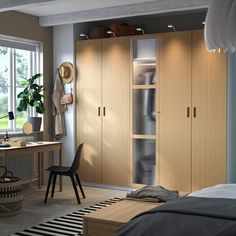 a bedroom with a bed, desk and closets in the corner next to a window