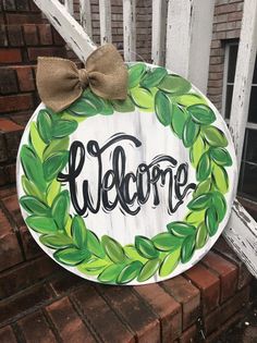 a welcome sign with a bow on the front porch