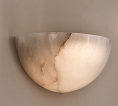 a large white bowl mounted to the side of a wall next to a light fixture