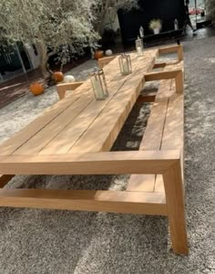 a long wooden table sitting in the middle of a gravel field with pumpkins on it