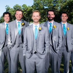 a group of men standing next to each other wearing gray suits and blue ties with yellow flowers on their lapels