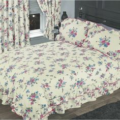 a bed with floral bedspread and matching comforter in front of a window