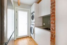 a washer and dryer in a room with wood flooring next to a brick wall