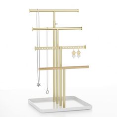 a gold jewelry rack with three necklaces and two earring holders on top of it