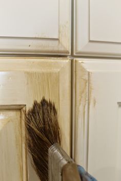 a brush that is sticking out of the side of a cabinet door with some paint on it