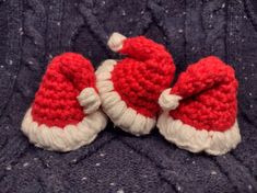 two knitted santa hats sitting on top of a blue blanket next to each other