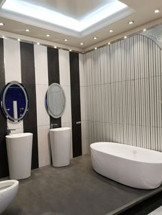 a modern bathroom with black and white stripes on the walls, two sinks and a round bathtub