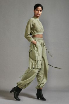 Green three fourth sleeves crop top in textured cotton with ribbed waistline, neckline and sleeve hem. Paired with a baggy-fit cargo pants with strap details on pockets. - Aza Fashions Cropped Cotton Pants With Pockets, Cotton Relaxed Fit Cropped Bottoms, Relaxed Fit Cotton Bottoms With Cropped Hem, Relaxed Fit Cropped Cotton Bottoms, Cotton Crop Top With Elastic Waistband, Spring Cropped Hem Cotton Bottoms, Spring Cotton Cropped Hem Bottoms, Spring Cotton Bottoms With Cropped Hem, Relaxed Fit Cropped Tops With Elastic Waistband