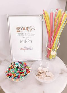 a table topped with lots of candy next to a glass vase filled with colorful straws