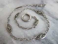 Beautifully crafted, this early 20th century watch chain is composed of 800-900 silver and hallmarked with two crabs as visible in photo ten. Despite the chain's age the links are in excellent condition and very strong. Likewise, the dog clip clasp is in good condition with good alignment. The bolt ring will need to be pushed into place as the tension has been affected by years of use but still has good alignment and holds well. The length of the chain is shorter than a modern chain but it makes Victorian Watch, Bolt Ring, Dog Clip, Watch Chain, Choker Necklaces, Short Necklace, Belle Epoque, Favorite Jewelry, Antique Silver