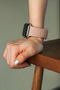 a woman's hand on top of a wooden chair with an apple watch band