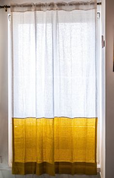 a yellow and white curtain hanging on the side of a window