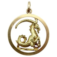 Rendered in beautiful detail, this stoic Capricorn stands upright with curving elements in the horns and tail. It is mounted in a flat circle, giving the charm a framework. The edge of the charm is finished like a coin, with ridging around the outer rim. The frame is flat, while the Capricorn is three dimensional on both sides so that the medallion can be worn facing either way. This well-sculpted 14k gold vintage piece is a great rendering of the water goat.  Capricorn is the zodiac sign for the birthdays December 22- January 21, depicted as a sea goat with the body of goat and tail of a fish. Capricorns are known for being down to earth, intelligent, ambitious, and hardworking.  The pendant is 1 1/4” across. The bail is 5.5 x 7.9 mm. It weighs 9 grams. Marked on the bail as 14k. Capricorn Necklace, Collectible Round Zodiac Sign Jewelry, Yellow Gold Zodiac Sign Charm Necklace With Round Pendant, Boy Silhouette, Gold-plated Zodiac Sign Round Pendant Jewelry, Capricorn Pendant, Vintage Charm Bracelet, Gold Charm Bracelet, Dog Charms