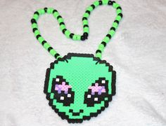 a green and black beaded necklace with an alien face