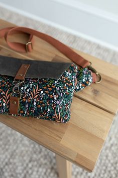 a purse sitting on top of a wooden table next to a bag with a leather strap