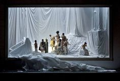 a group of people standing in front of a white sheet covered room with mannequins