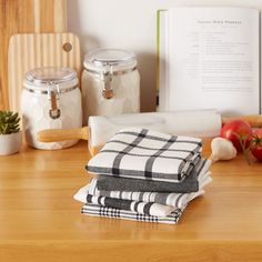 three kitchen towels stacked on top of each other next to some vegetables and utensils