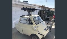 an old white car parked in front of a house with a camera attached to it