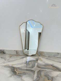 a mirror sitting on top of a marble counter next to a white wall and floor