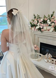 a bride in her wedding dress looking at herself in the mirror with flowers behind her