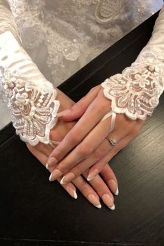 two hands holding each other on top of a wooden table with white laces and beads