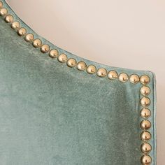 the back of a green velvet bed with gold studded trimmings on it