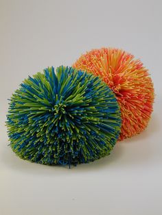 two balls of yarn sitting next to each other on a white surface with one colorful ball in the middle